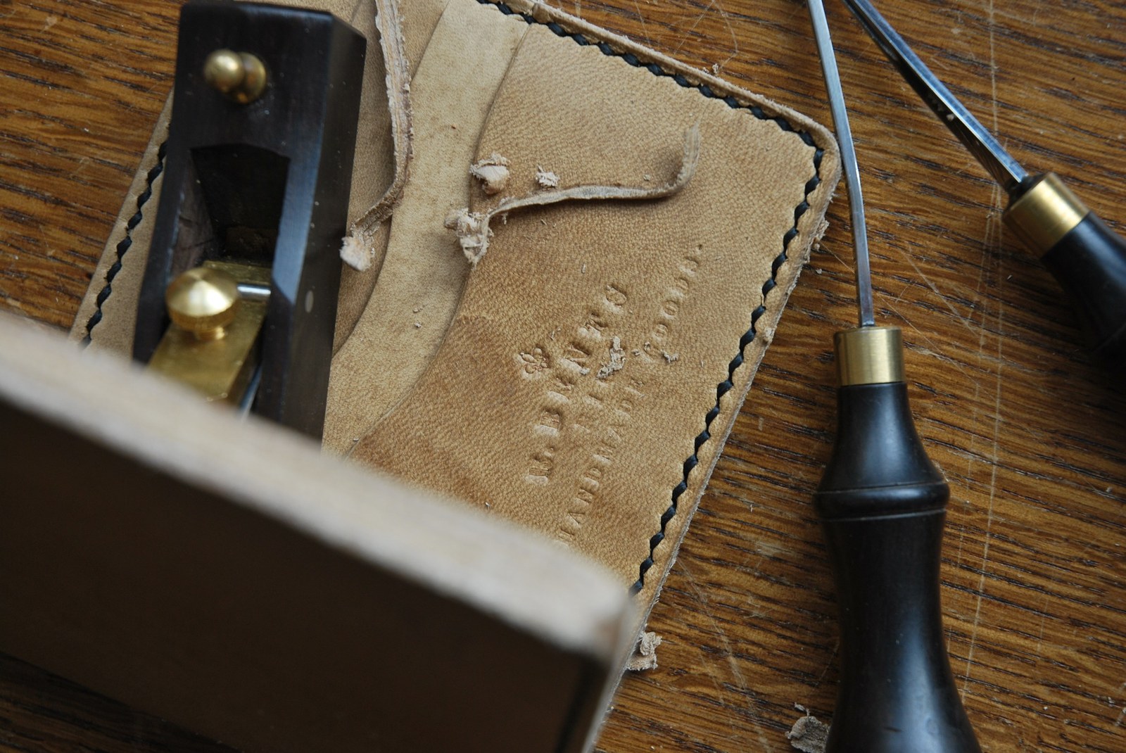 Leatherwork bench with tools and hand stitching